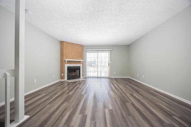 unfurnished living room featuring a fireplace, dark wood-type flooring, and a textured ceiling