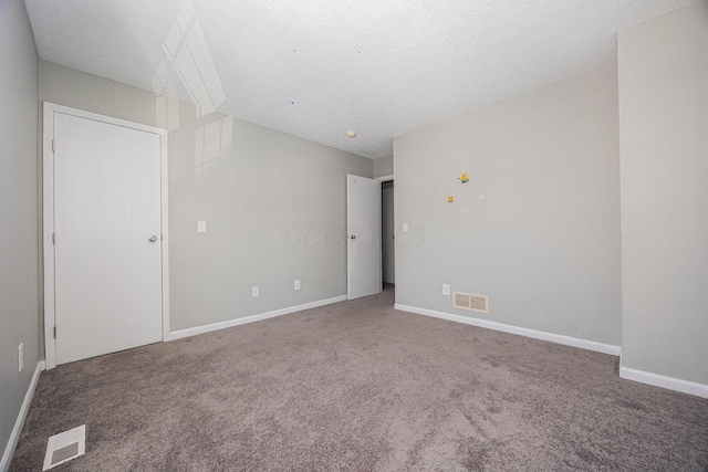 empty room with carpet floors and a textured ceiling