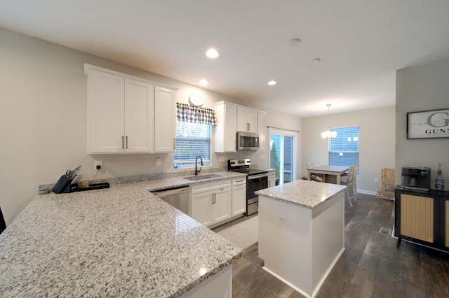 kitchen featuring white cabinetry, sink, hanging light fixtures, stainless steel appliances, and a kitchen island