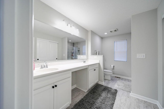 bathroom featuring vanity, hardwood / wood-style flooring, toilet, and a shower with shower door