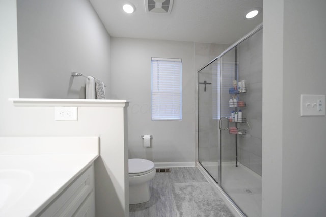 bathroom featuring hardwood / wood-style floors, vanity, toilet, and a shower with shower door