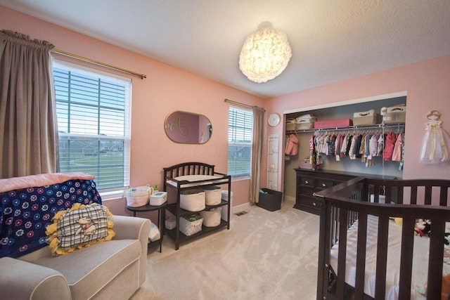 bedroom with a closet, light colored carpet, and a nursery area