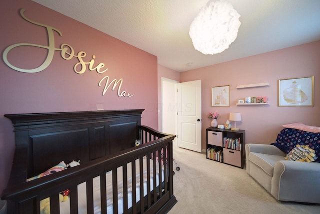 bedroom featuring a crib, light carpet, and a chandelier