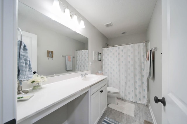 bathroom with walk in shower, hardwood / wood-style floors, a textured ceiling, toilet, and vanity