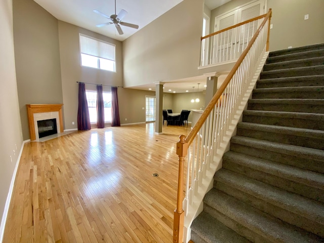 interior space with a high ceiling, light hardwood / wood-style flooring, ornate columns, and ceiling fan