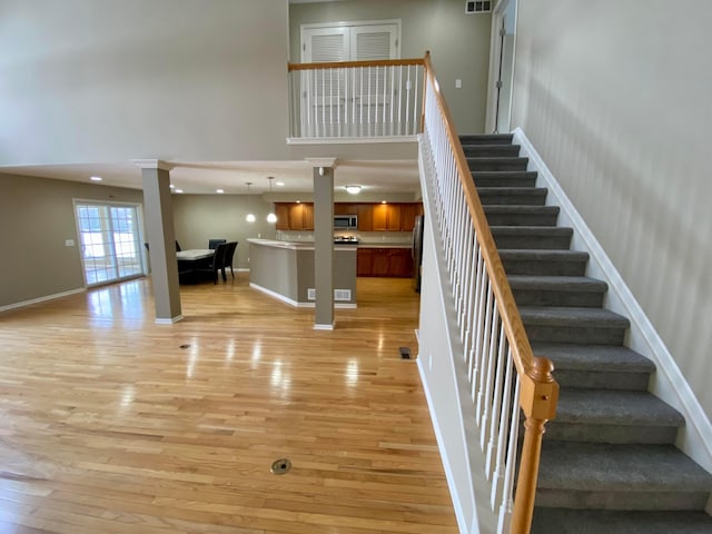 stairs featuring hardwood / wood-style floors and a high ceiling