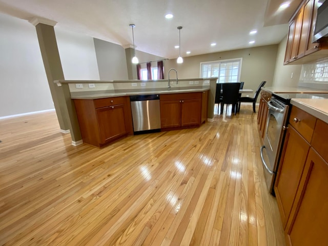 kitchen with sink, stainless steel appliances, pendant lighting, decorative backsplash, and light wood-type flooring