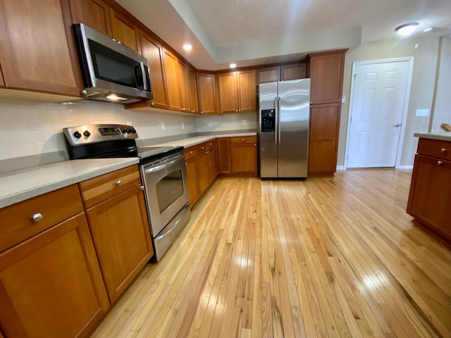 kitchen featuring decorative backsplash, light hardwood / wood-style floors, and appliances with stainless steel finishes