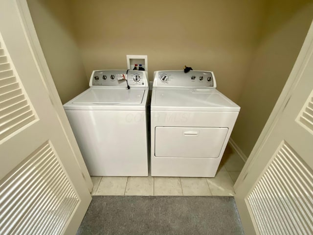 laundry area with washer and clothes dryer and light tile patterned floors