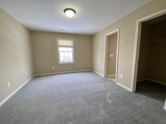 unfurnished bedroom with carpet floors, a spacious closet, and a closet