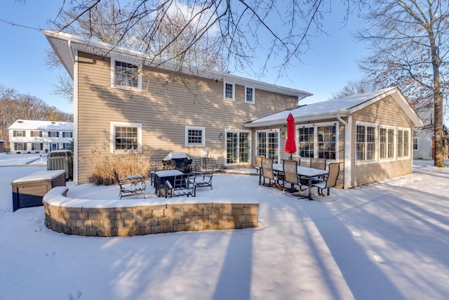 snow covered rear of property featuring central AC unit