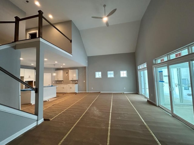 unfurnished living room with ceiling fan and high vaulted ceiling