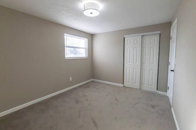 unfurnished bedroom with light colored carpet and a closet