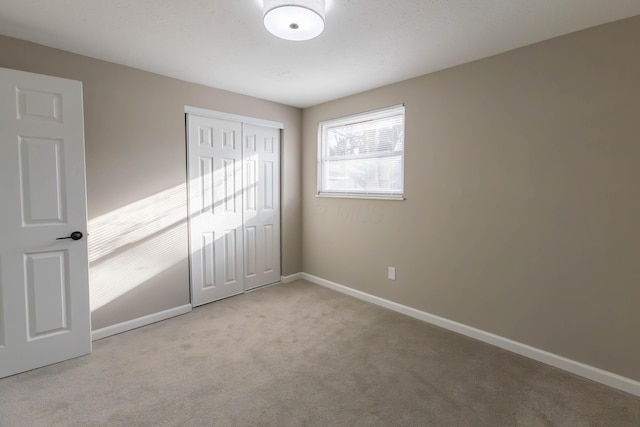 unfurnished bedroom with light colored carpet and a closet