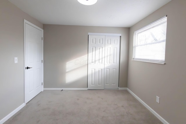 unfurnished bedroom with light carpet and a closet