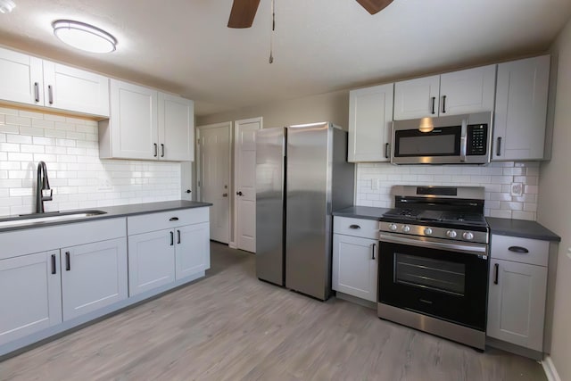 kitchen with decorative backsplash, appliances with stainless steel finishes, ceiling fan, sink, and white cabinets