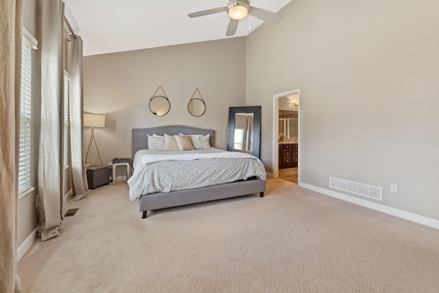 carpeted bedroom featuring ceiling fan, ensuite bathroom, and high vaulted ceiling