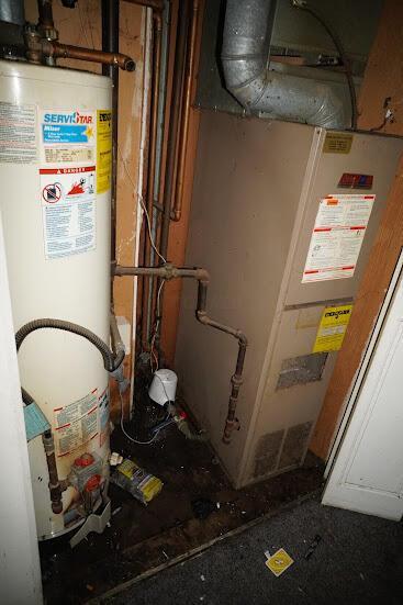 utility room featuring gas water heater and heating unit