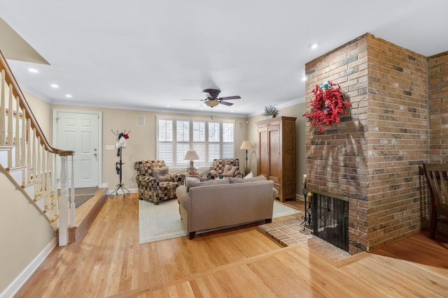 living room with ceiling fan, light hardwood / wood-style floors, crown molding, and a brick fireplace