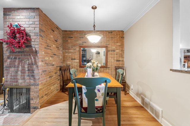 dining space featuring a fireplace, hardwood / wood-style floors, and crown molding