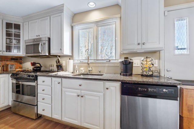 kitchen with white cabinetry, sink, stainless steel appliances, and light hardwood / wood-style flooring