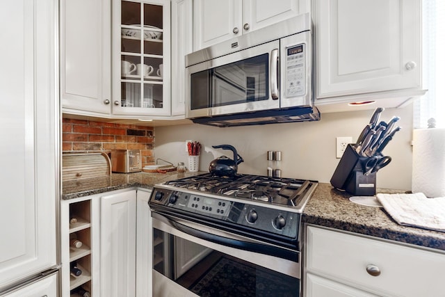 kitchen featuring white cabinetry, stainless steel appliances, and dark stone counters