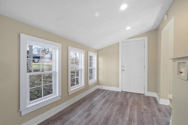 interior space featuring a textured ceiling, light hardwood / wood-style flooring, and vaulted ceiling