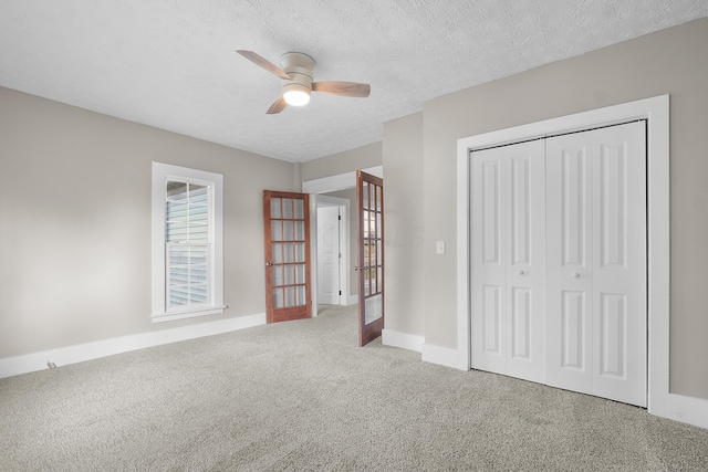 unfurnished bedroom featuring ceiling fan, french doors, carpet floors, a textured ceiling, and a closet