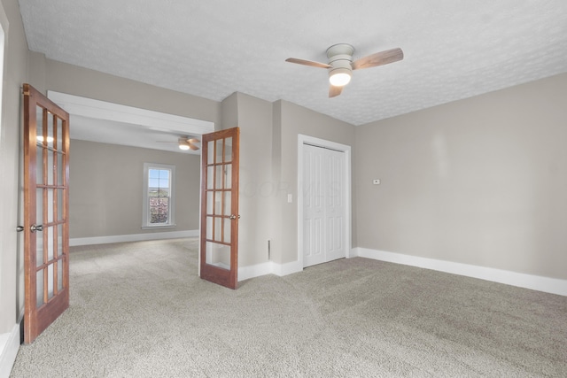 carpeted spare room featuring ceiling fan, a textured ceiling, and french doors