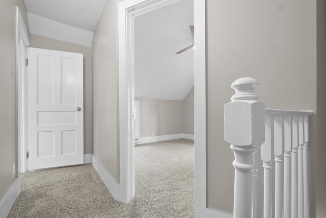 hallway featuring carpet, a textured ceiling, and lofted ceiling