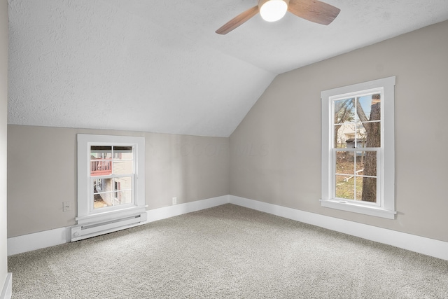 bonus room featuring ceiling fan, a baseboard heating unit, carpet floors, a textured ceiling, and vaulted ceiling