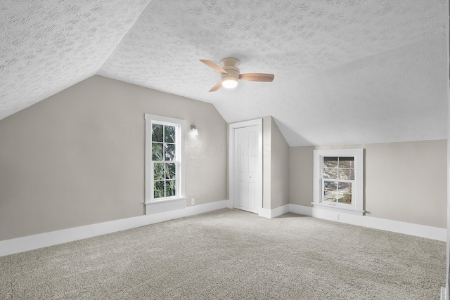 additional living space with a textured ceiling, ceiling fan, carpet floors, and vaulted ceiling