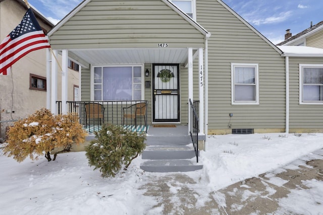 snow covered property entrance with covered porch