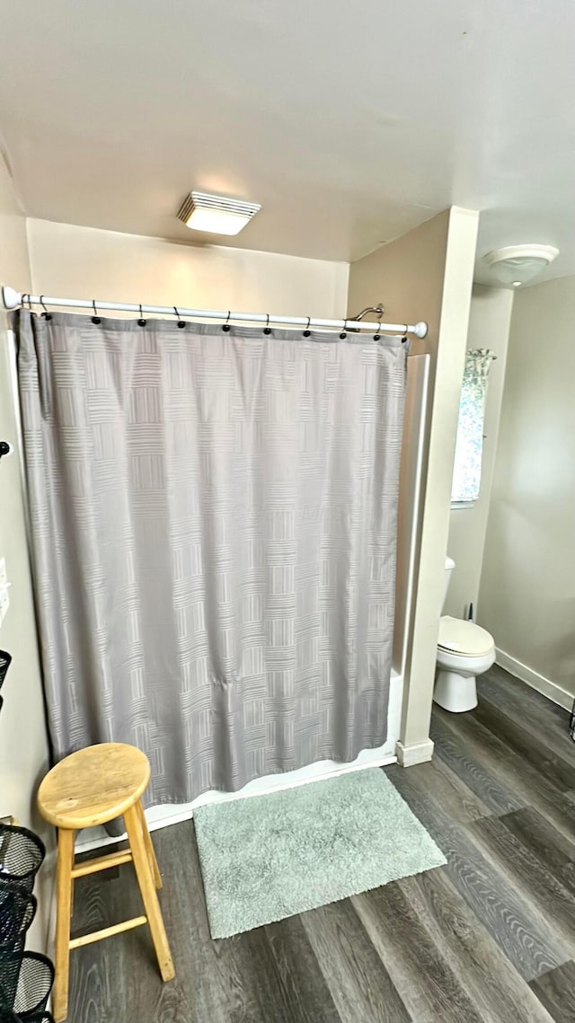 bathroom with hardwood / wood-style flooring, toilet, and shower / bath combo with shower curtain