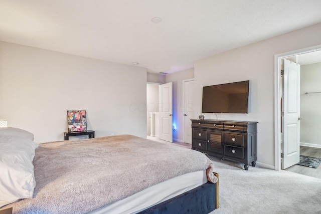 bedroom featuring ensuite bathroom and light carpet