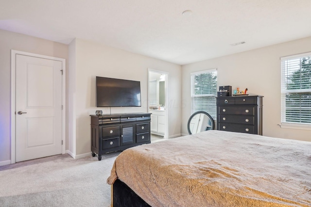 bedroom with light colored carpet and connected bathroom