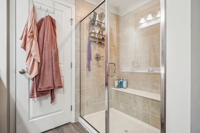 bathroom with a shower with shower door and hardwood / wood-style flooring