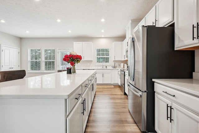 kitchen featuring white cabinets, appliances with stainless steel finishes, a textured ceiling, and a kitchen island