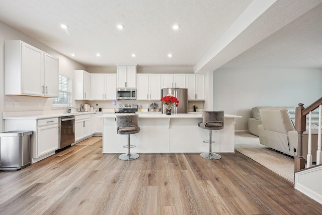 kitchen with a breakfast bar, appliances with stainless steel finishes, a center island, and white cabinetry