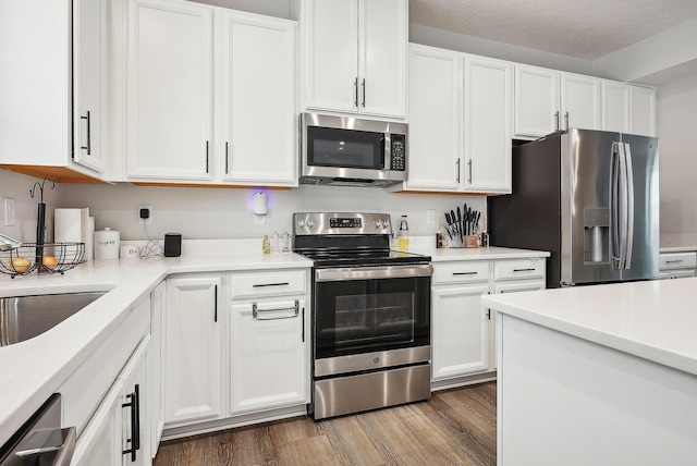 kitchen featuring white cabinets, appliances with stainless steel finishes, a textured ceiling, and dark hardwood / wood-style floors