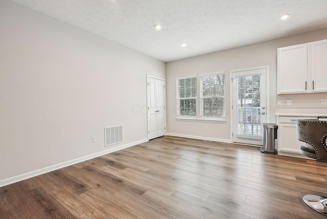 unfurnished living room with a textured ceiling and light hardwood / wood-style flooring