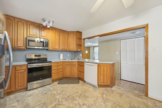 kitchen featuring backsplash, sink, ceiling fan, kitchen peninsula, and stainless steel appliances