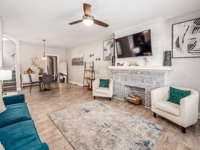 living room featuring ceiling fan, a fireplace, and hardwood / wood-style flooring