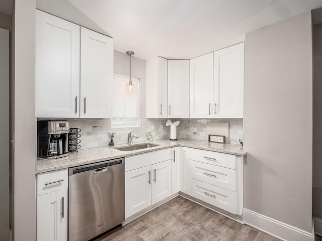 kitchen with light hardwood / wood-style floors, stainless steel dishwasher, decorative backsplash, sink, and white cabinets