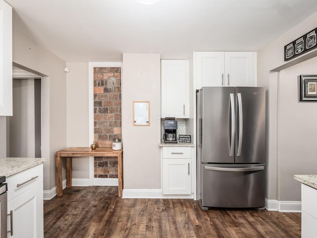 kitchen with dark hardwood / wood-style floors, white cabinetry, stainless steel fridge, and light stone countertops