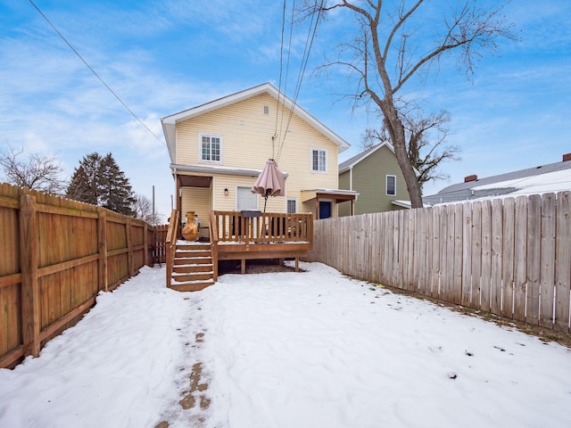 snow covered back of property featuring a deck