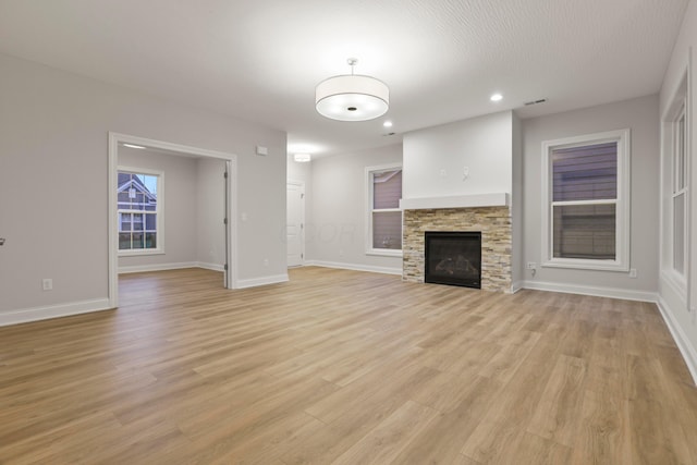 unfurnished living room featuring a fireplace and light hardwood / wood-style floors