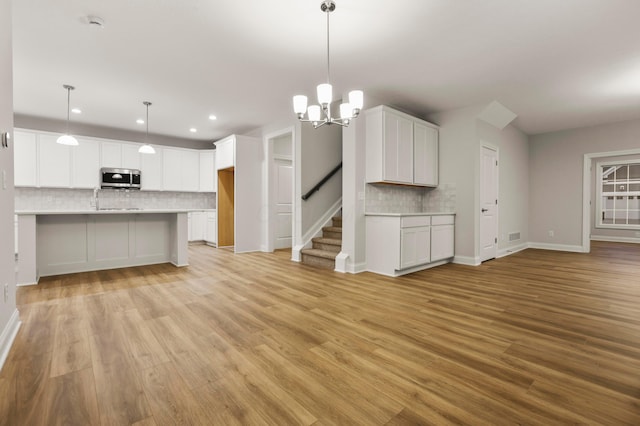 kitchen featuring decorative light fixtures, white cabinetry, and light hardwood / wood-style flooring