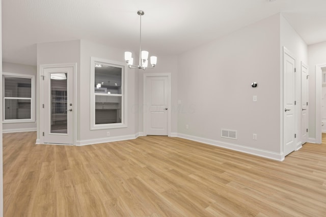 unfurnished dining area featuring a chandelier and light hardwood / wood-style floors