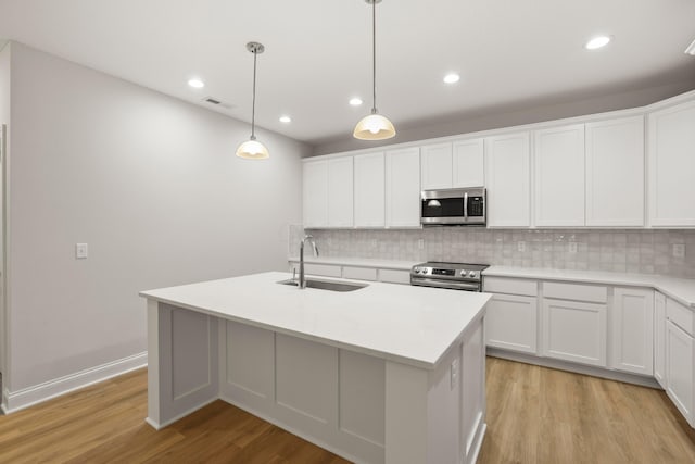 kitchen featuring appliances with stainless steel finishes, an island with sink, white cabinetry, and sink